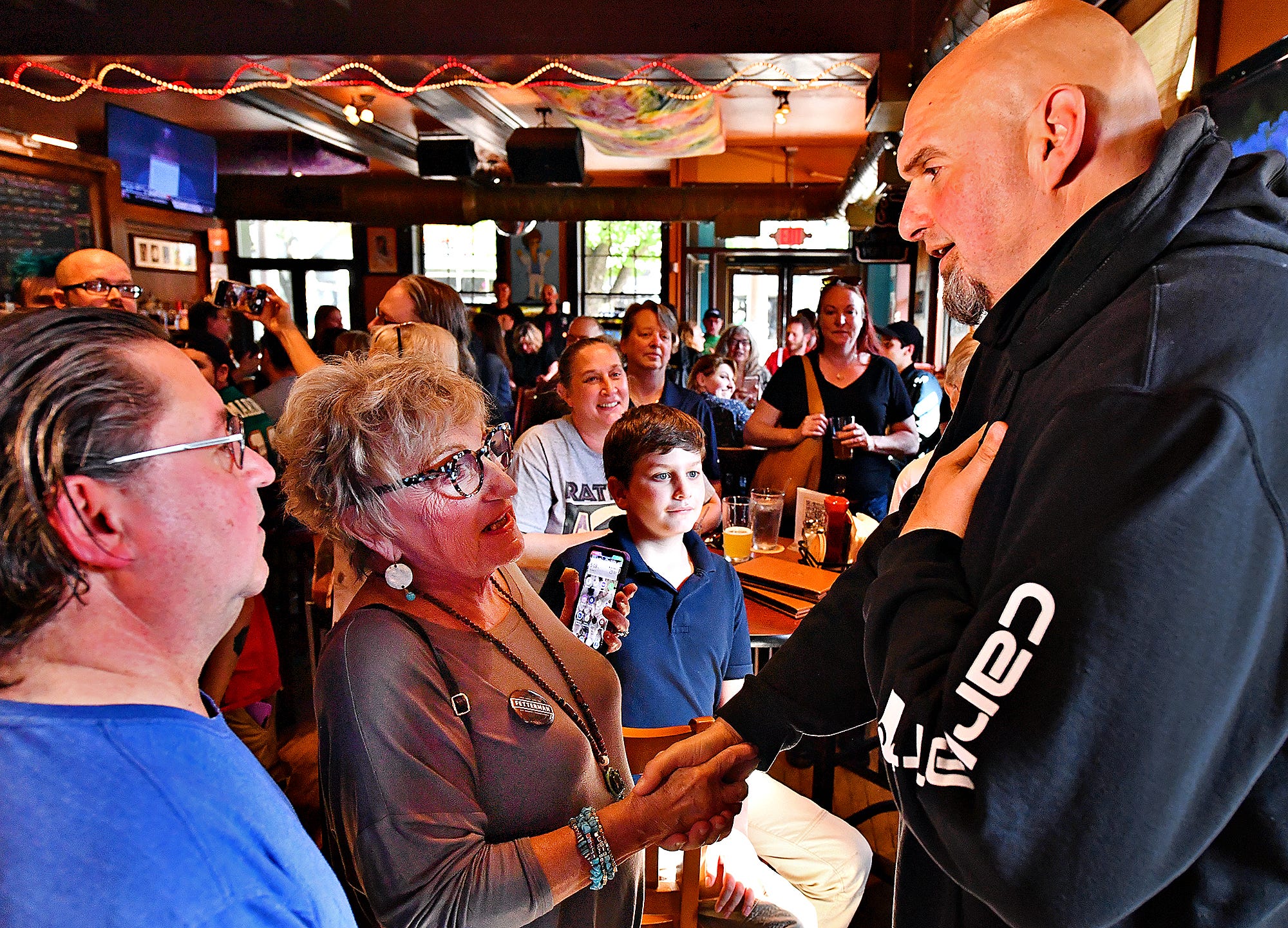 From left, Fred Wallick, of Dover Township, and Joshua Peterman, 11, of West York Borough, look on as Sherry Sharp, of New Salem Borough greets Lt. Gov. John Fetterman during a campaign stop at Holy Hound Taproom in York City, Thursday, May 12, 2022. Fetterman is running for U.S. Senate. Dawn J. Sagert photo