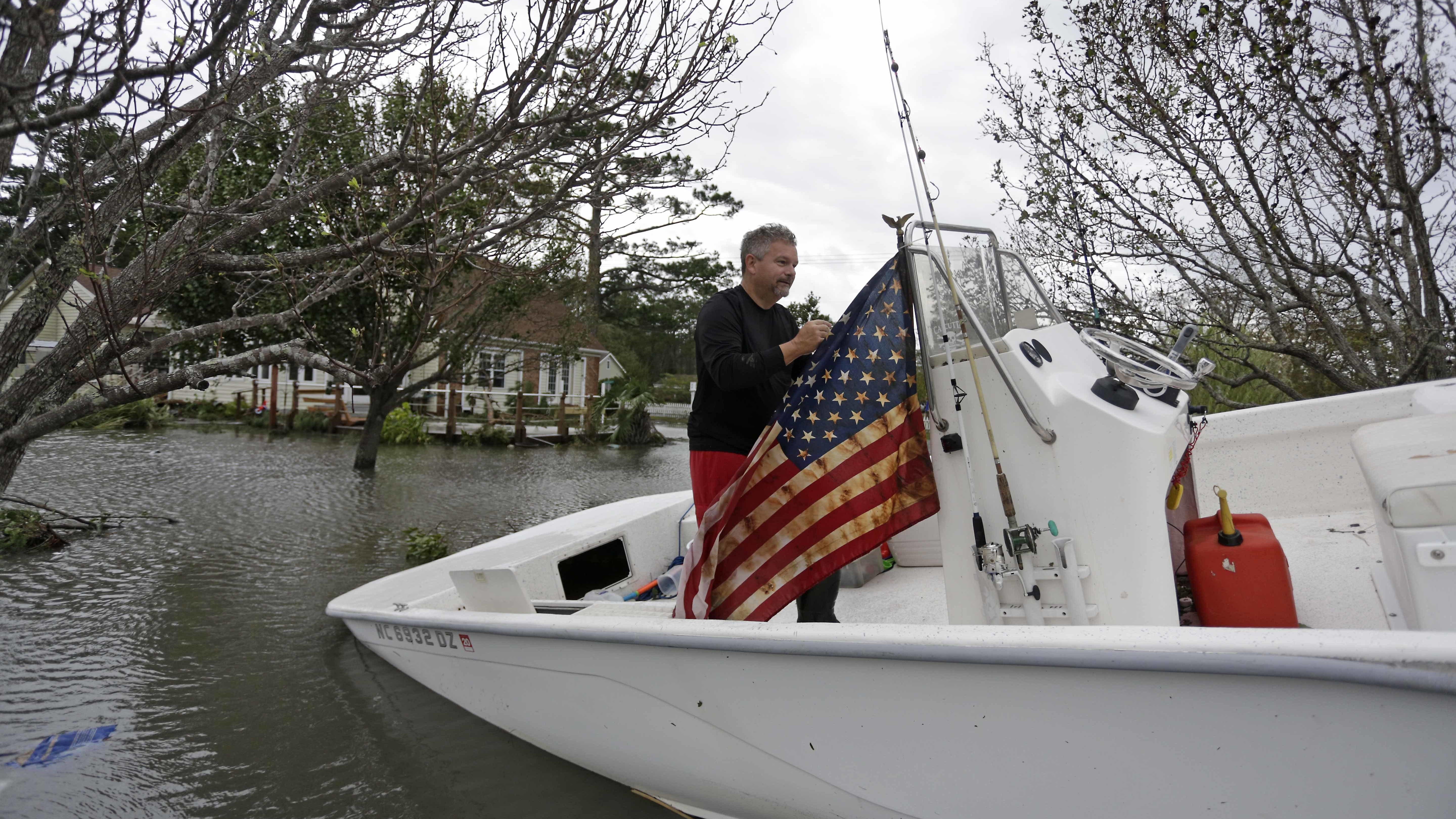 Jonathan Griffin hangs an American Flag on his boat after Hurricane Florence hit Davis N.C.,Saturday, Sept. 15, 2018. Griffin said "I'm going to hang this in defiance of Hurricane Florence". (AP Photo/Tom Copeland)