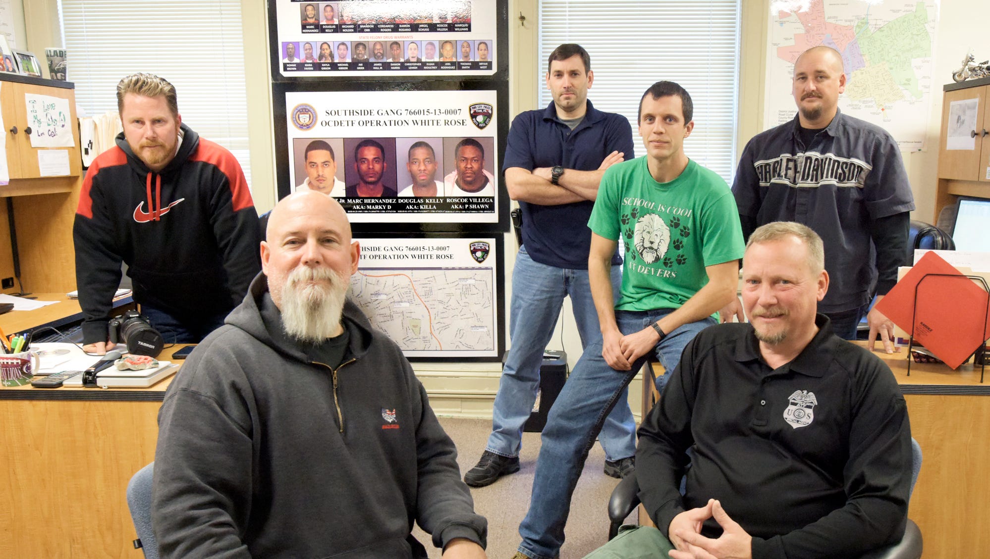 York City Narcotics Squad members, from left, Detective Scott Nadzom, Detective First Class Andy Shaffer, Officer Stephen Aderhold, Officer Zach Pelton, ATF Special Agent Scott Endy and Detective Bart Seelig, pose in their headquarters in an old York City fire station. The poster on the wall references the Southside Gang whose members are facing federal prosecution due to the efforts of the group. (Bill Kalina - The York Dispatch)