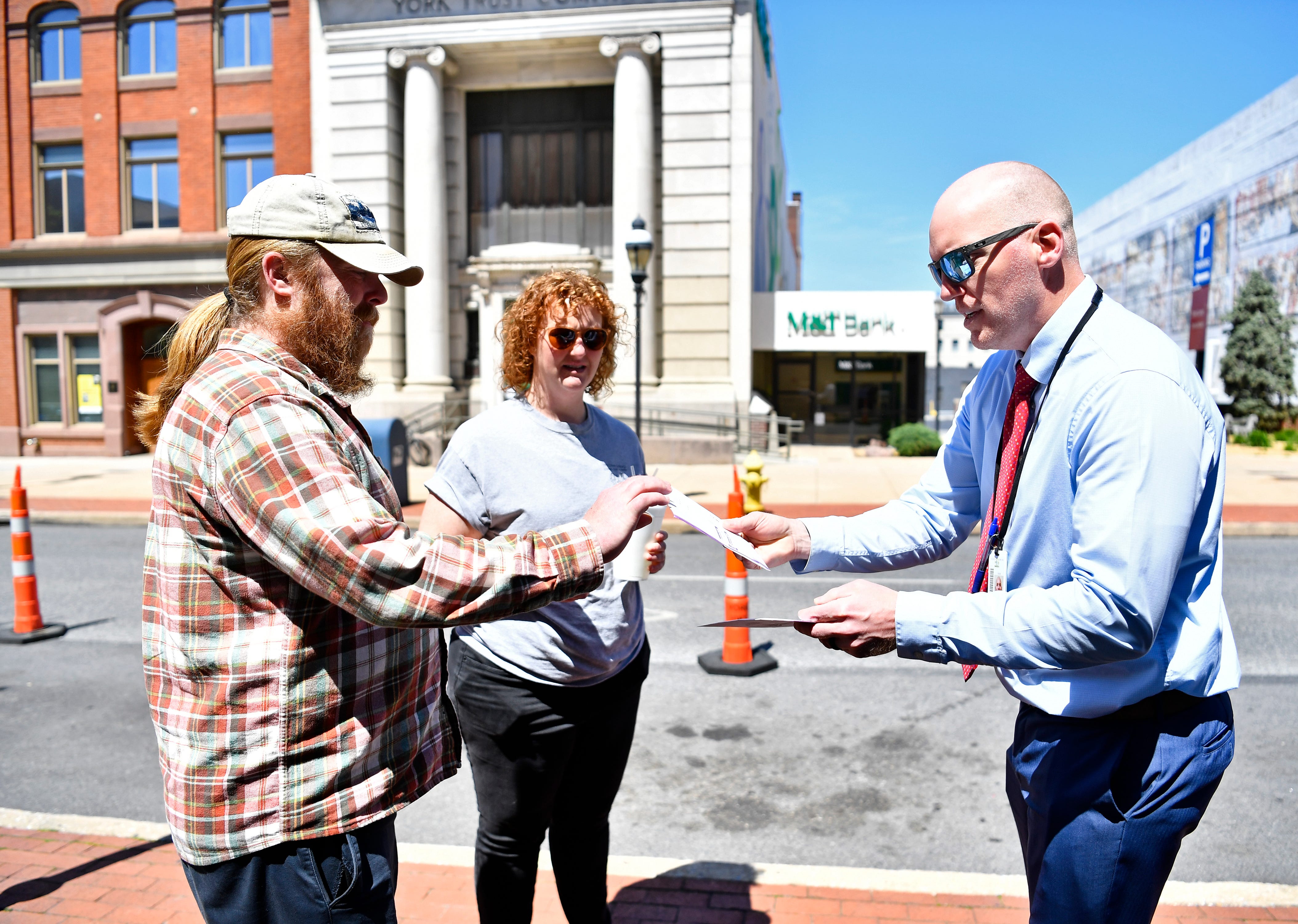 From left, Tim Gilbert and Claire Gilbert, both of West Manchester Township, hand their ballots to York County Prison Warden Adam Ogle before they are placed in a secured drop box in front of the York County Administrative Center on East Market Street in York City during Primary Election Day, Tuesday, April 23, 2024. (Dawn J. Sagert/The York Dispatch)