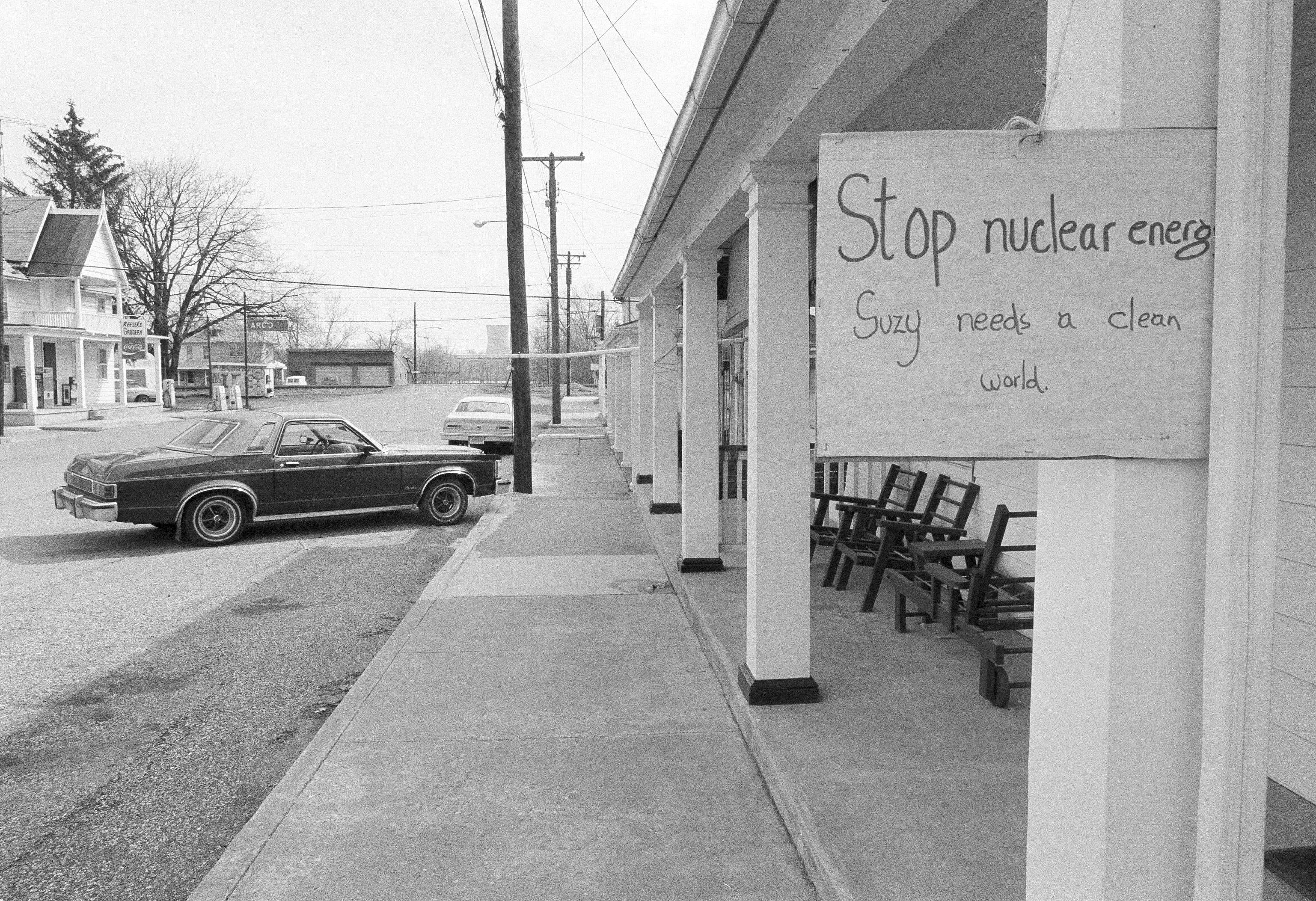A sign on a building in Goldsboro, Penn, with a deserted street and nuclear plant cooling towers in the background was the scene here, March 31, 1979. Many of the residents within a five-mile area have evacuated. (AP Photo/R.C. Greenawalt)