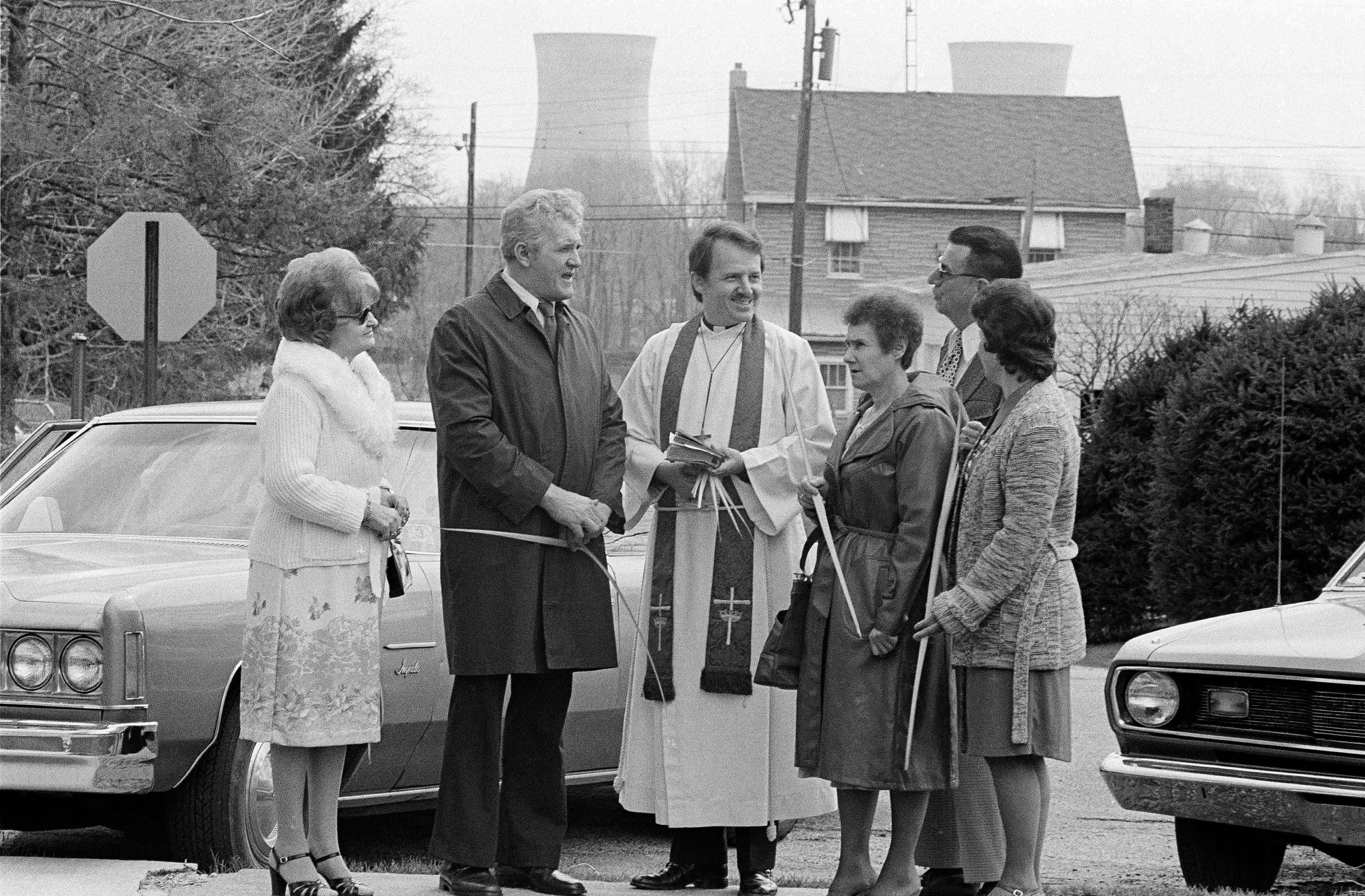 Rev. Frederick Wedemeyer talks with parishioners outside the Zion Lutheran Church in Goldsboro, Pa., following the Palm Sunday services, April 8, 1979. In the background are cooling towers of Three Mile Island nuclear power plant that is shut down following an accident causing nuclear radiation to leak into the atmosphere. (AP Photo/Prouser)
