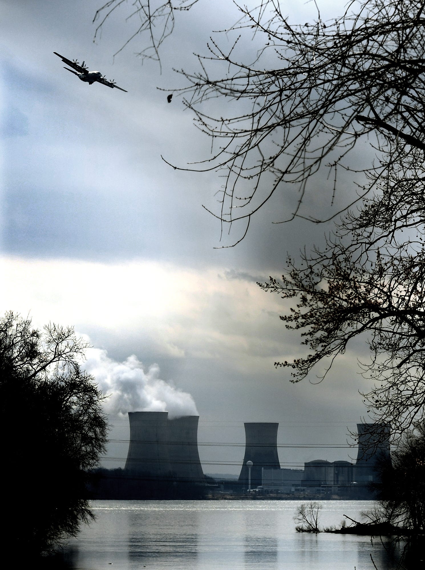 A military aircraft flies near the Three Mile Island Nuclear Generating Station viewed from the borough of Royalton, Dauphin County, Friday, March 15, 2019. The plant's Unit 2 reactors have been shut down since the March 28,1979, partial meltdown. Bill Kalina photo