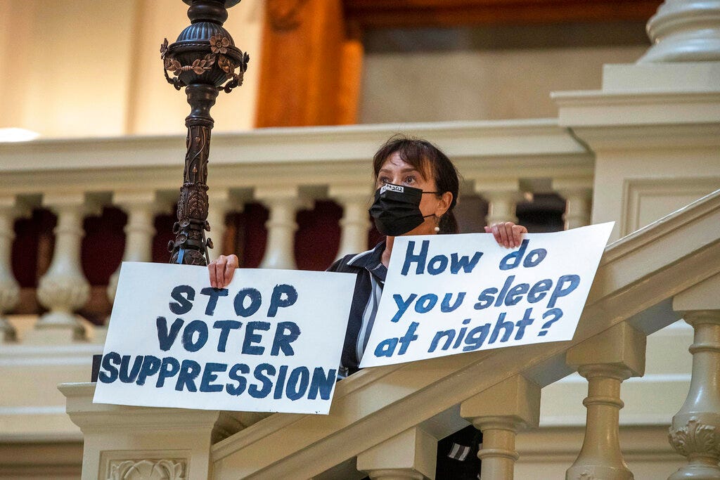Ann White of Roswell holds protest signs on the North Wing stairs of the Georgia State Capitol building on day 38 of the legislative session in Atlanta, Thursday, March 25, 2021. "It ain't over yet," said White. "I look forward to going door-to-door working against everybody that voted for (SB 202)." The Georgia state House has passed legislation brought by Republicans that could lead to a sweeping overhaul of state election law. (Alyssa Pointer/Atlanta Journal-Constitution via AP)