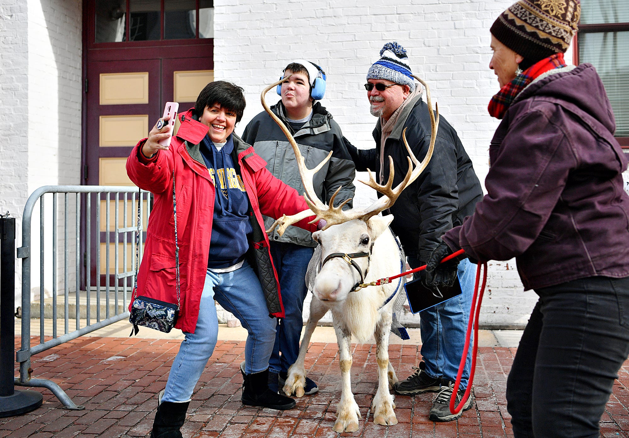 Zoann Parker, right, of TNZ Farm, secures Snow, an 8-year-old reindeer as she poses for a photo with, from left, Dianne Newman, Matthew Newman, 14, and Jeff Newman, all of West Manchester Township, during the 8th annual FestivICE event in downtown York City, Saturday, Jan. 15, 2022. "She's retired," said Parker of Snow. "This is all she does 'cuz she's a diva." Dawn J. Sagert photo