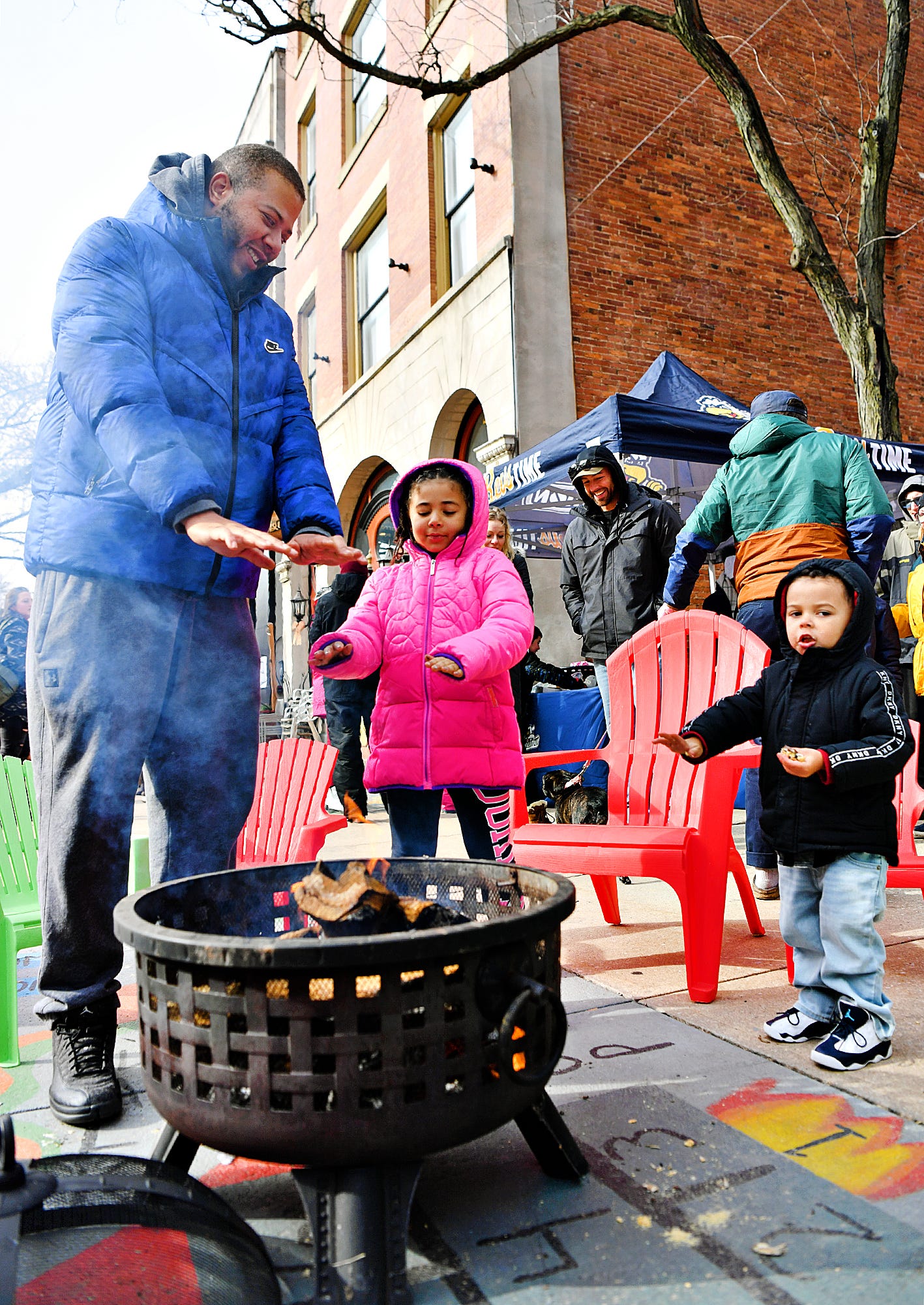 From left, Jeffrey Johnson, of York City, warms his hands near the fire pit with his children Laila Johnson, 6, and Haiden Johnson, 2, during the 8th annual FestivICE event in downtown York City, Saturday, Jan. 15, 2022. Dawn J. Sagert photo