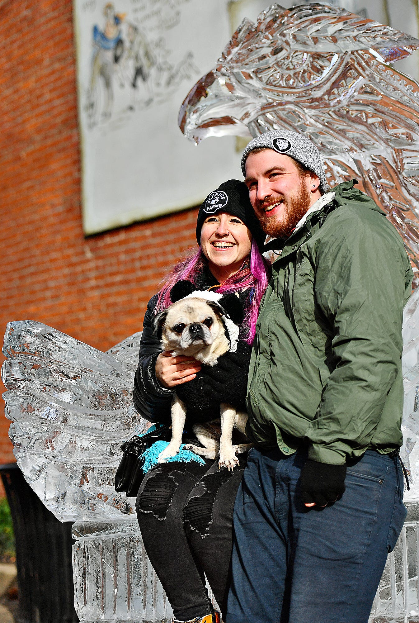 From right, Mike Johnson, Kaitlyn Ulrich, and 14-year-old pug Bella, all of Baltimore, pose for a photo together with the ice sculpture throne during the 8th annual FestivICE event in downtown York City, Saturday, Jan. 15, 2022. Dawn J. Sagert photo