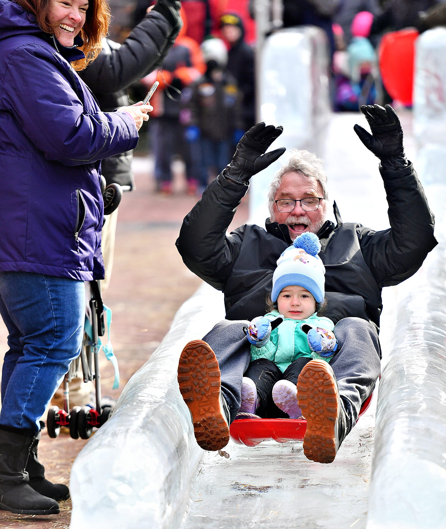 From left, Pam Murphy looks on as her husband Peter Murphy, both of Bethlehem, goes down the 40-foot WellSpan Ice Slide with their granddaughter Norah McComsey, 3, of Wrightsville, during the 8th annual FestivICE event in downtown York City, Saturday, Jan. 15, 2022. Dawn J. Sagert photo