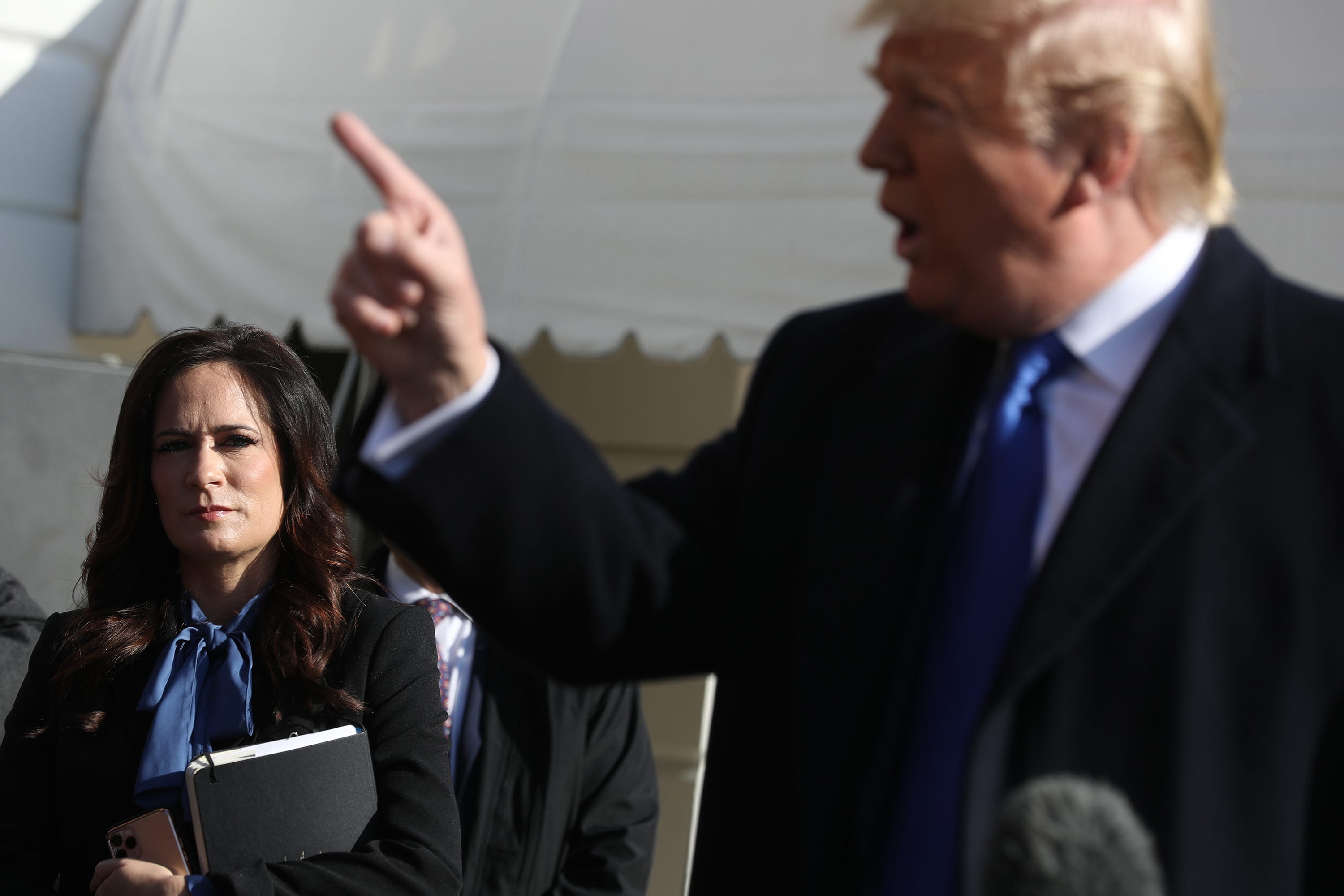 White House press secretary Stephanie Grisham, left, listens to President Donald Trump talk to reporters before he boards Marine One at the White House on Nov. 8, 2019, in Washington, D.C. (Chip Somodevilla/Getty Images/TNS)