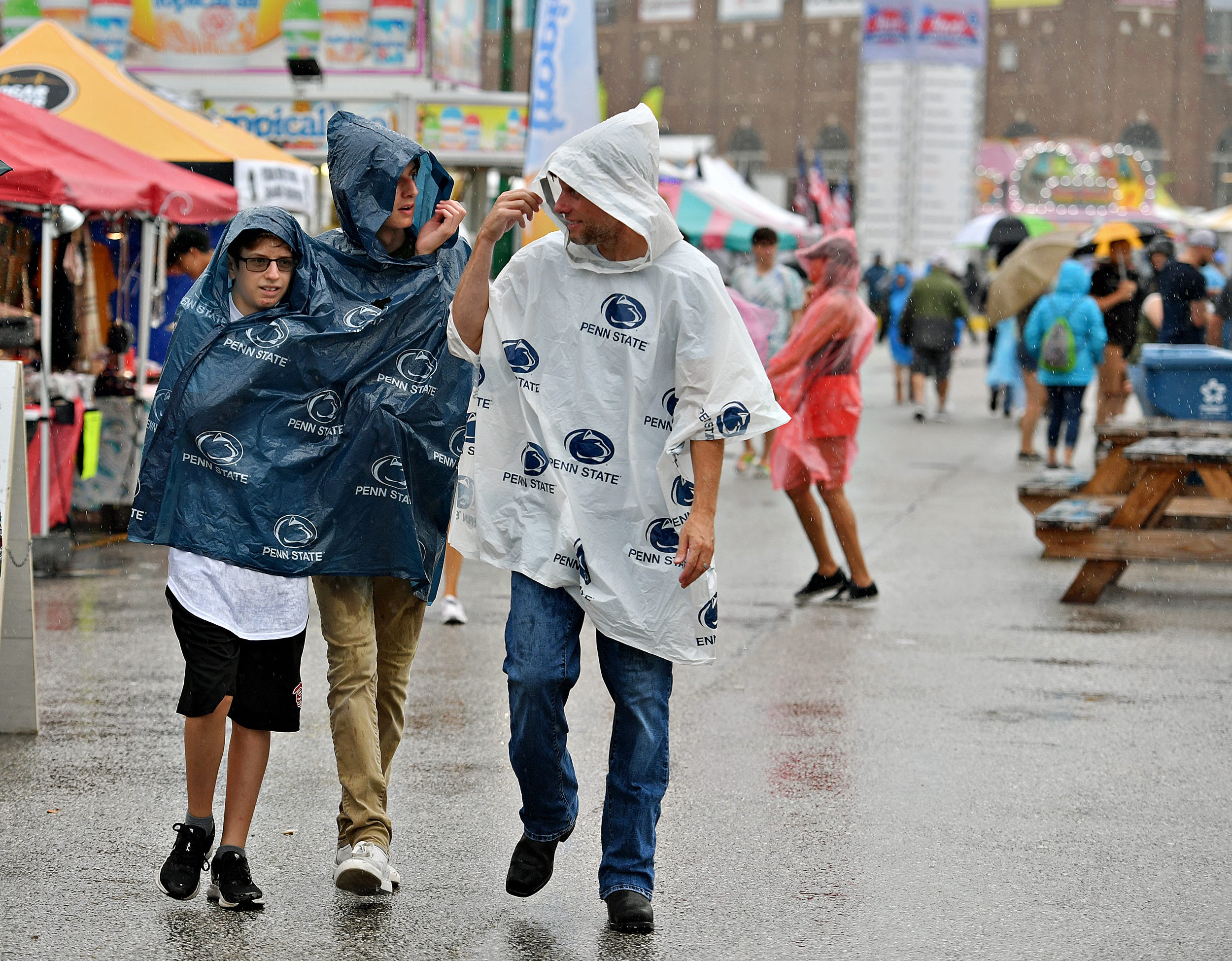 From right, David Fogle, Blaze Fogle, 16, and Brock Fogle, all of Springettsbury Township, brave the rain during the final day of York State Fair in York, Pa., Sunday, July 31, 2022. Dawn J. Sagert/The York Dispatch